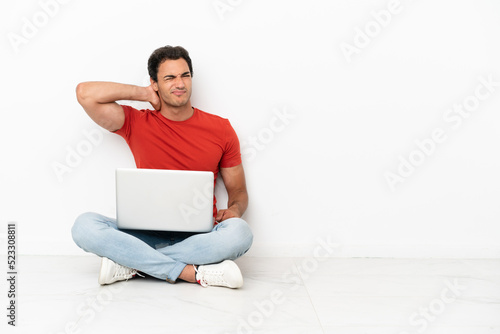 Caucasian handsome man with a laptop sitting on the floor with neckache photo