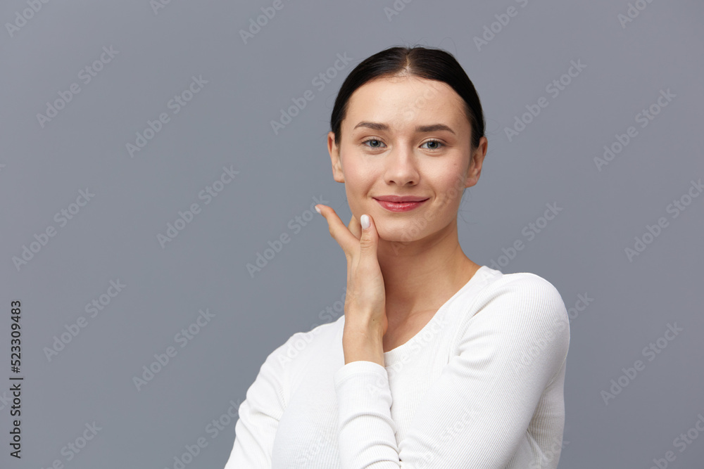 a gentle woman stands against a dark background in a tight white T-shirt, joyfully leaning her palm against her neck smiling sweetly a gentle woman stands against a dark background in a tight white T-shirt, joyfully leaning her palm against her neck smiling sweetly