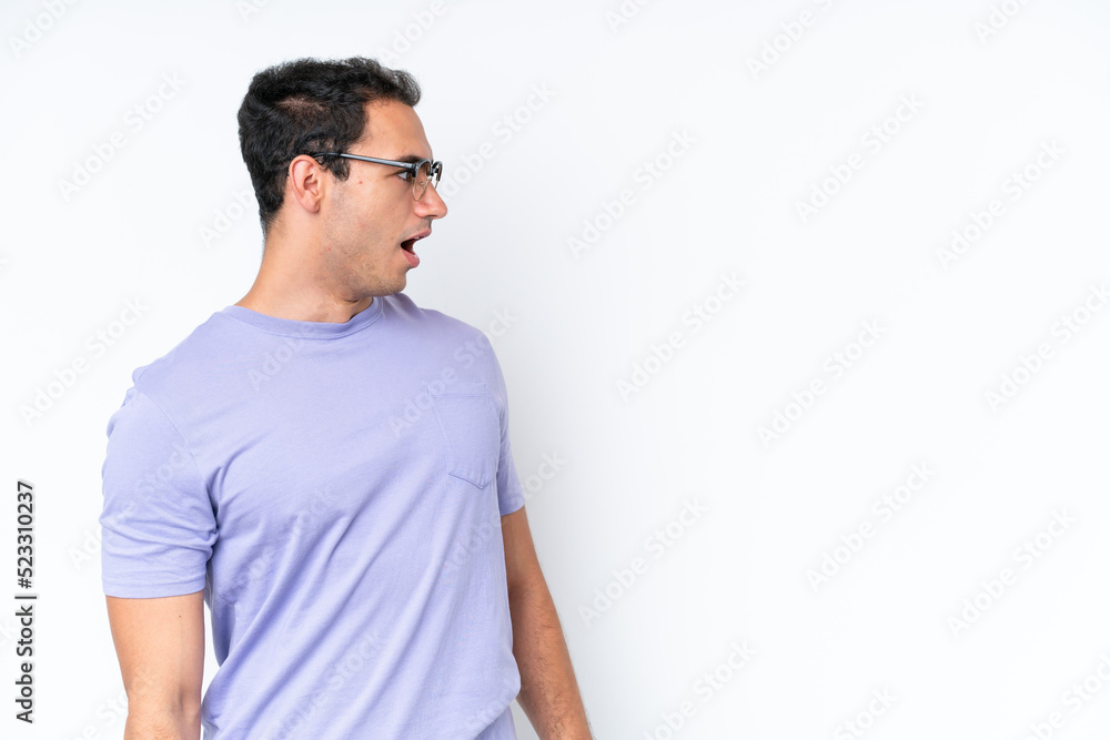 Fototapeta premium Young caucasian man isolated on white background doing surprise gesture while looking to the side