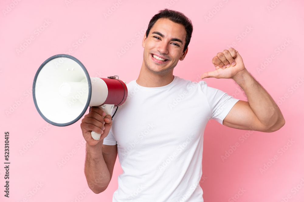 Young caucasian man isolated on pink background holding a megaphone and proud and self-satisfied Young caucasian man isolated on pink background holding a megaphone and proud and self-satisfied