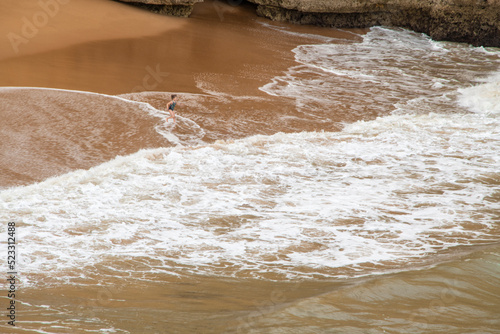 One person on the beach with brawn sand and white waves