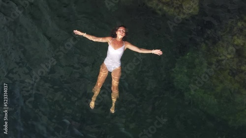 Wallpaper Mural Woman floating sea. Aerial top view of young pretty woman in white swimsuit floating on water surface in crystal clear turquoise sea. Vacation at Paradise. Ocean relax, travel and vacation. Torontodigital.ca