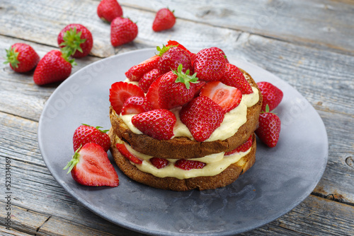 Traditional roasted Italian panettone tiramisu with vanilla custard curd and strawberries served as close-up in a design plate