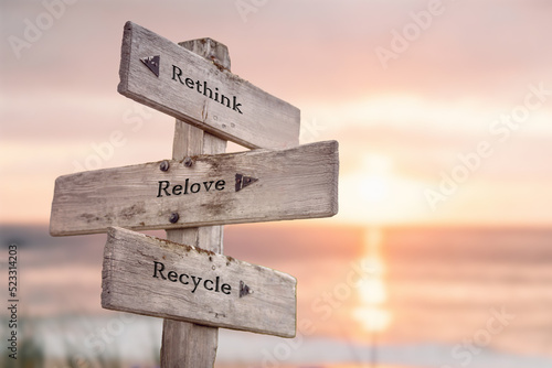 rethink relove recycle text quote caption on wooden signpost outdoors at the beach during sunset. photo