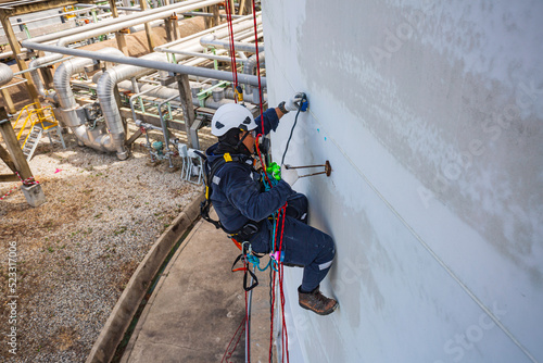 Top view male worker inspection wearing safety first harness rope safety line working at a high place on tank roof spherical