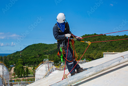 Male worker inspection wearing safety first harness rope safety line working at a high place on tank roof spherical gas