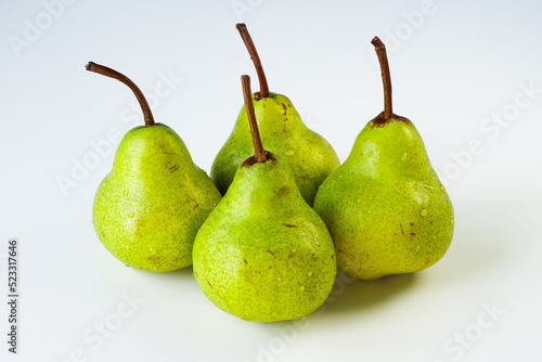 Green Williams pears isolated on a light surface in close-up. Several ripe fruits of yellow-green color covered with water droplets are on the table