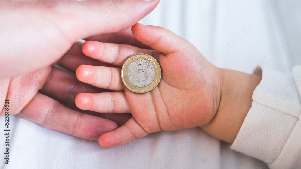 Inflation and financial security concept: Close up of newborn baby holding a euro coin Inflation and financial security concept: Close up of newborn baby holding a euro coin