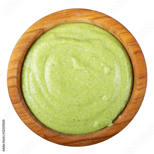 Green diet cream broccoli soup in a wooden plate isolated on white background. Vegan food.