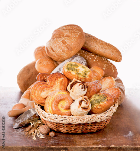 Flour products . Wicker basket with different types of bread and sweet buns on white background