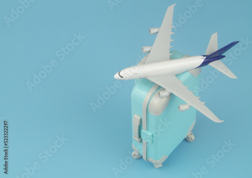 Airplane model on mini suitcase on blue background with copy space for text. Travel and vacation concept.