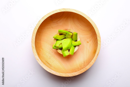 avocado cut into small pieces in a wooden bowl isolated on white background
