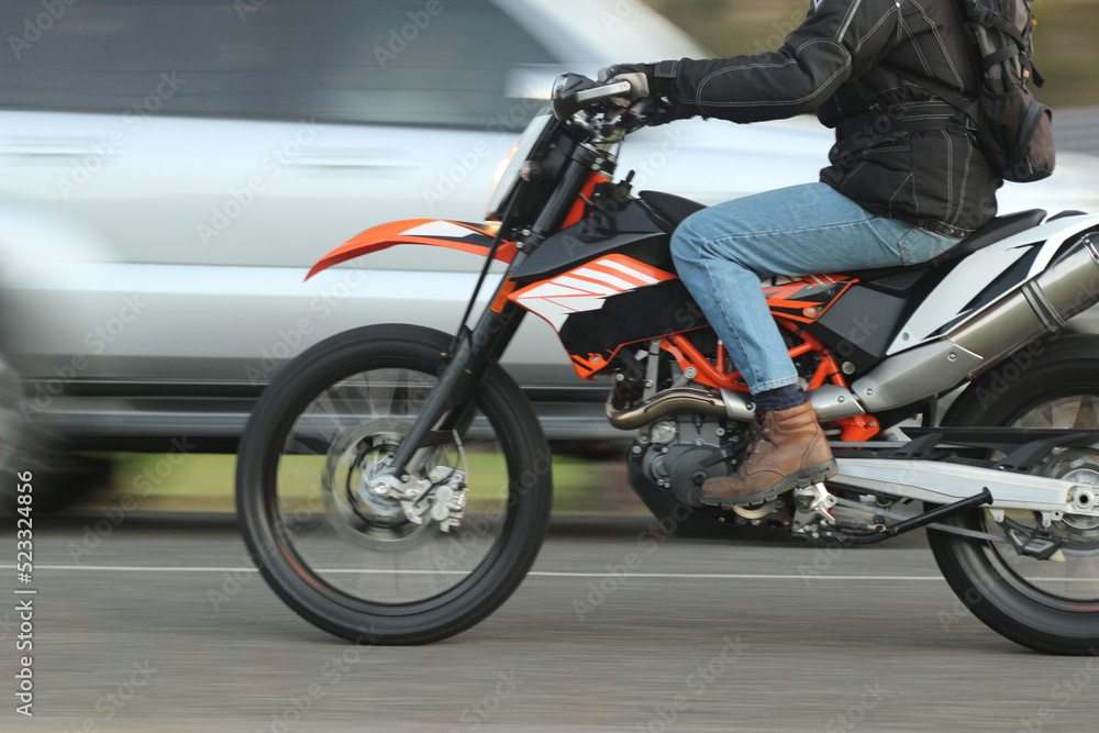 Close up of a man riding a motorbike past a car Close up of a man riding a motorbike past a car