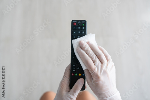 Wallpaper Mural Hand in glove usiing wet wipe  cleaning and disinfection high-touch household surfaces. Prevention of infection. The woman disinfects the TV remote control in hotel room. Top view Torontodigital.ca