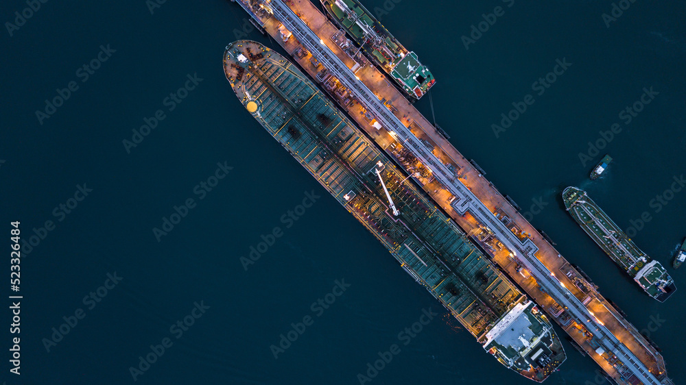 Aerial view tanker ship vessel unloading at port at night, Global business logistic import export oil and gas petrochemical with tanker ship transportation oil from dock refinery.