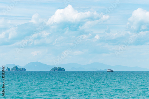 View of the turquoise sea and islands on a sunny summer day. A ship sails in the distance. Mountain silhouettes in the background.