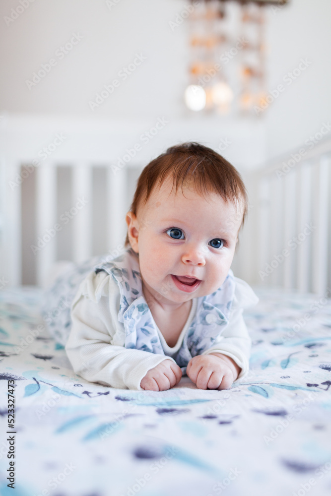 Happy Aussie baby smiling at tummy time in cot in bedroom Happy Aussie baby smiling at tummy time in cot in bedroom
