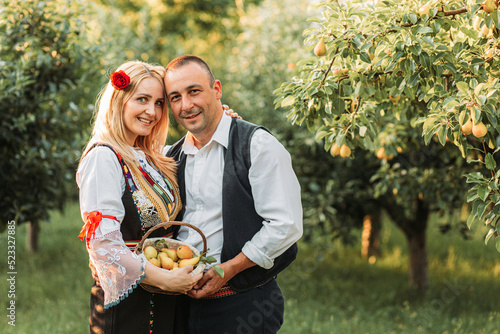 Young couple in Serbian traditional holding a basket with fresh pears