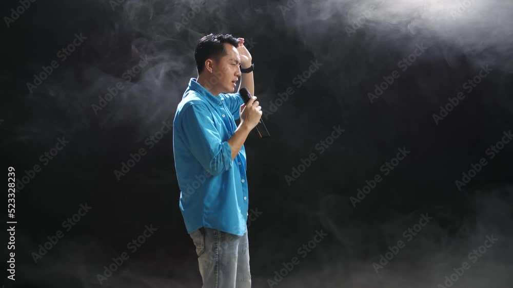 Side View Of Asian Man Holding A Microphone And Rapping On The Black Background
Side View Of Asian Man Holding A Microphone And Rapping On The Black Background