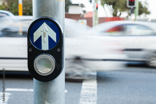 Traffic pedestrian crossing light button with cars zooming past photo