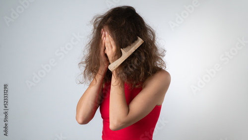 Upset woman with a tangled comb in her hair, problematic, naughty hair with split ends