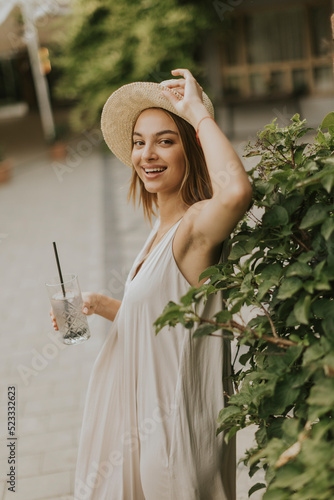 Young woman with hat drinki...