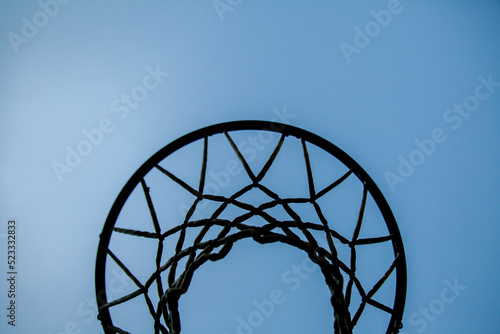 Silhouette of basketball hoop and net against blue sky photo