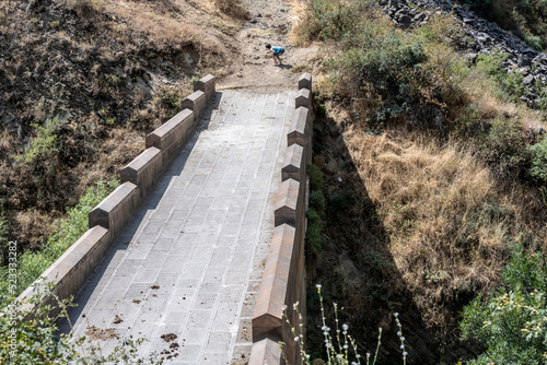 a stone bridge to nowhere and a tourist is looking at something on the edge of the bridge