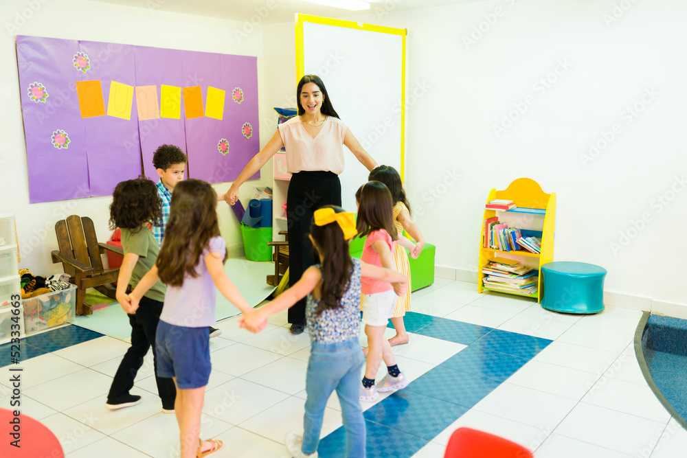 Fototapeta premium Teacher and kindergarten students playing a fun game at school
