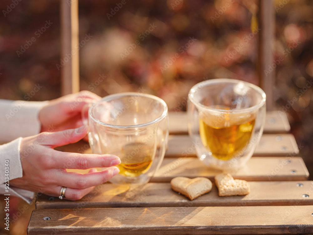 Drinking tea with cookies on wooden table. Cozy autumn mood scene in autumn park Drinking tea with cookies on wooden table. Cozy autumn mood scene in autumn park