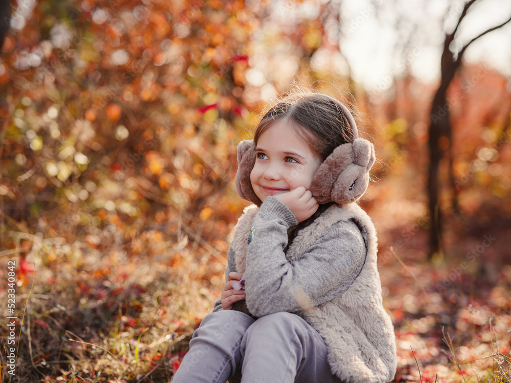 Portrait of small stylish beautiful model girl who stands in the autumn park at sunset Portrait of small stylish beautiful model girl who stands in the autumn park at sunset