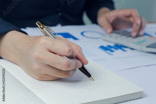 Business woman Write note and  analyzing data from market report.Business Financial Concept