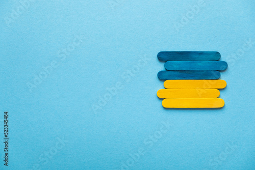 Blue and yellow wooden sticks. Flag of Ukraine on a blue background, free space
