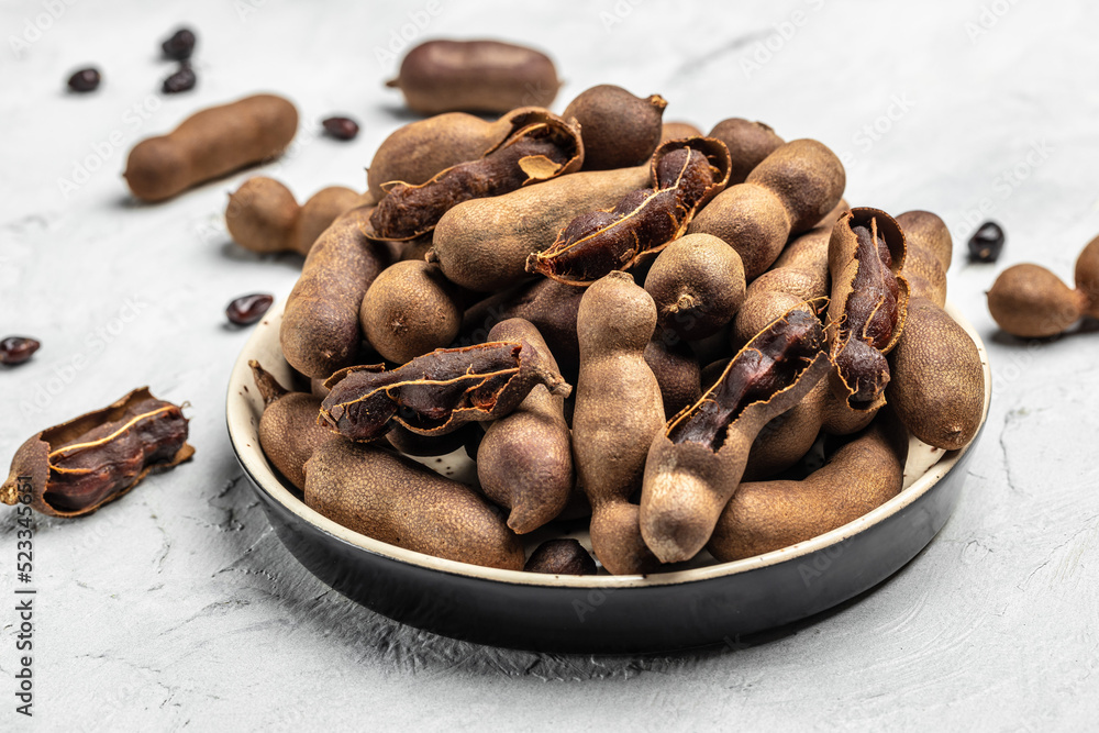 tamarinds beans in shell on a brown butchers block on a light background, healthy fruit. banner, menu, recipe place for text, top view tamarinds beans in shell on a brown butchers block on a light background, healthy fruit. banner, menu, recipe place for text, top view