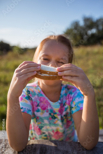 Girl holding sandwich with white bread. Snack on a picnic. 