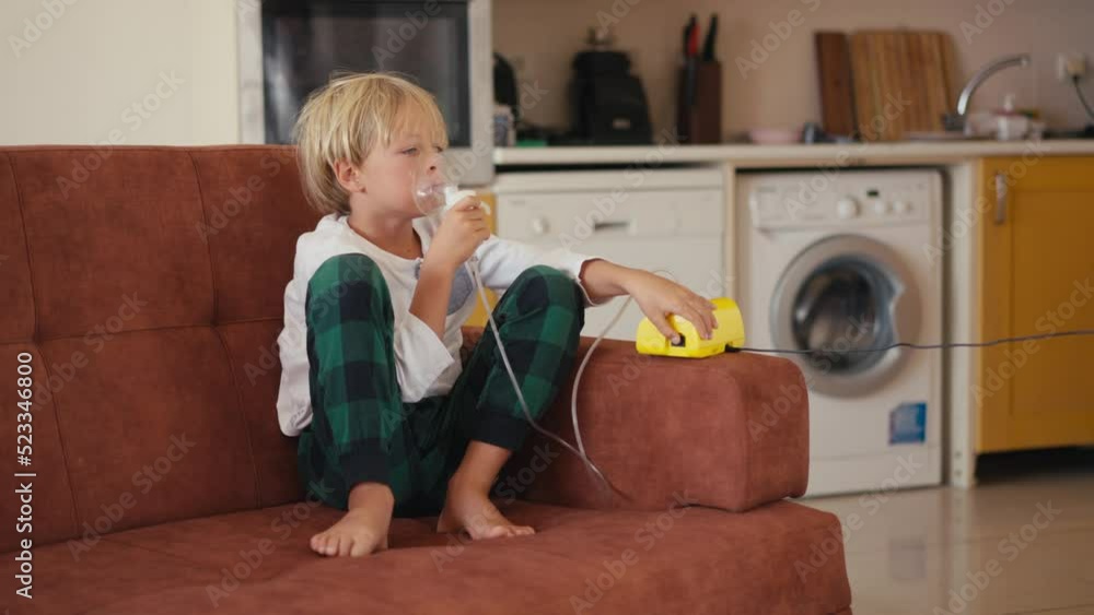 Child has respiratory infection or bronchitis, and he is breathing heavily. Blond Caucasian child with asthma problems inhales with tube in his mouth.High quality 4k footage Child has respiratory infection or bronchitis, and he is breathing heavily. Blond Caucasian child with asthma problems inhales with tube in his mouth.High quality 4k footage