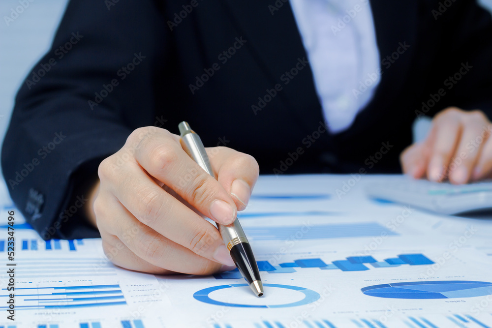 Businessman holding a profitability statistics analysis pen from a graph document in hand to plan profit. Businessman holding a profitability statistics analysis pen from a graph document in hand to plan profit.