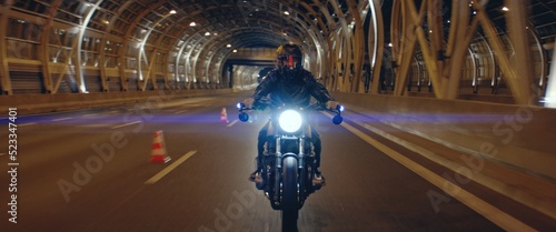 Biker riding his custom built cafe racer motorcycle through city at night. Shot with 2x anamorphic lens photo