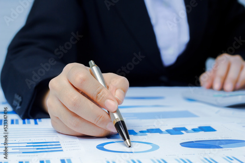 Businessman holding a profitability statistics analysis pen from a graph document in hand  to plan profit.
