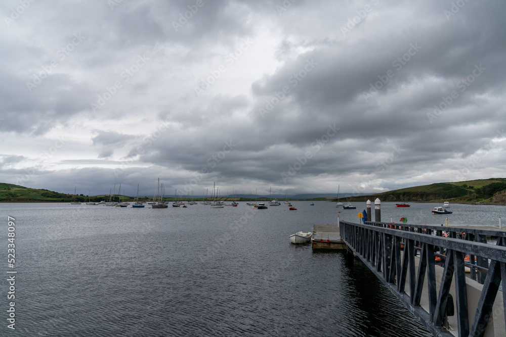 the Rosmoney Pier and dock with many sailboats and yachts anchored in the waters of Clew Bay under an overcast sky