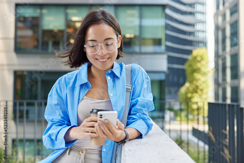 Photography Outdoor shot of beautiful Asian woman with short dark hair uses smartphone devic