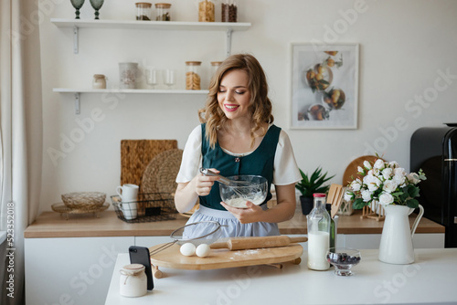 Beautiful girl cooks and looks at the recipe on the smartphone