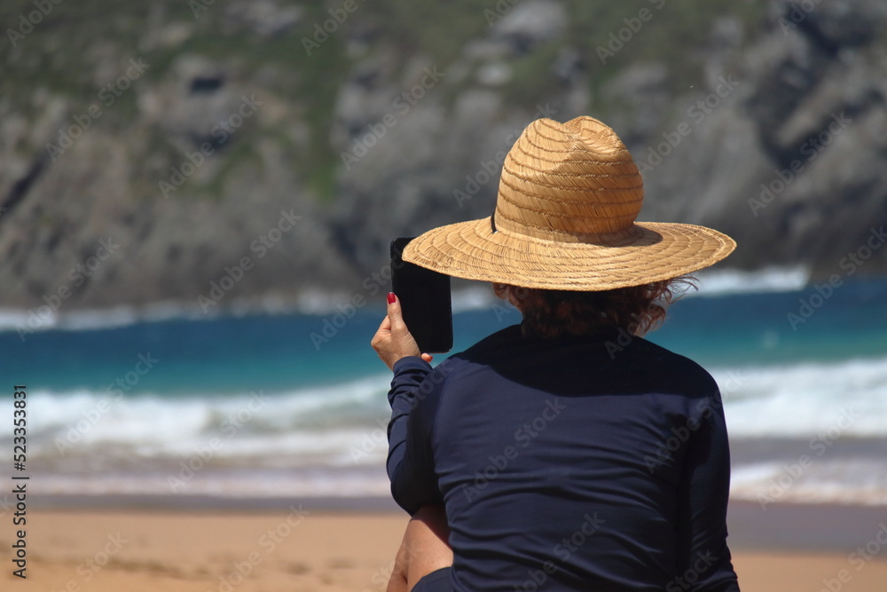 Beautiful middle age woman's hand using smart phone at beach. 