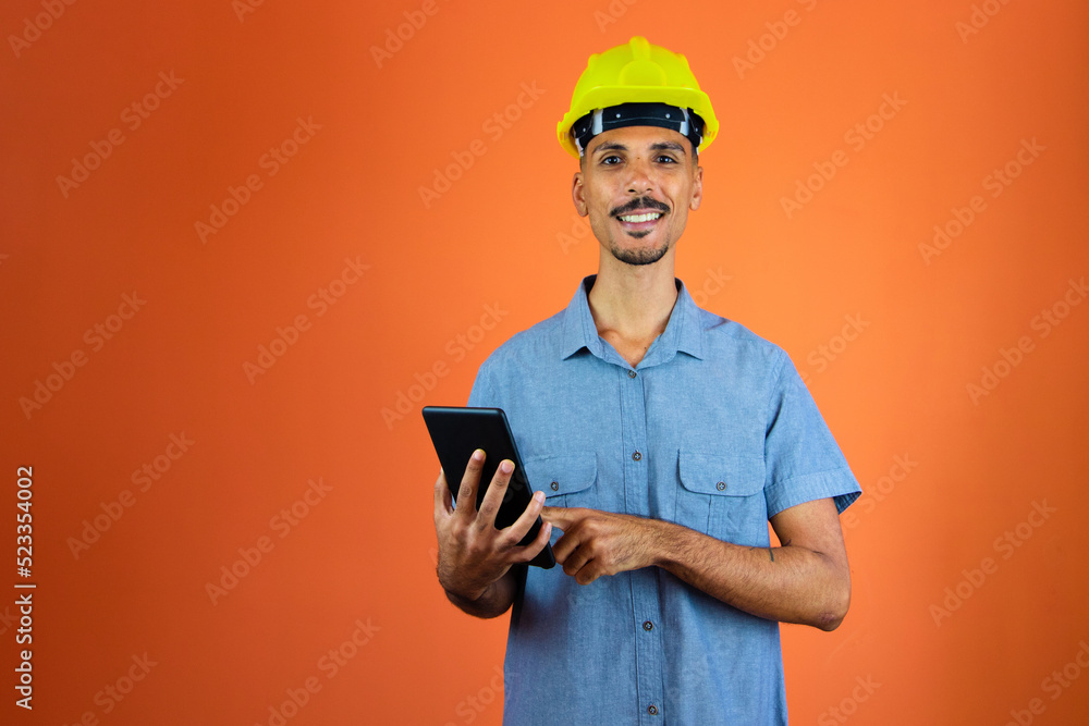 Engineers day - Black Man in Safety Helmet and Blue Shirt isolated. Engineer Holding Mobile. Engineers day - Black Man in Safety Helmet and Blue Shirt isolated. Engineer Holding Mobile.