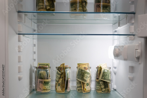 Dollars in a glass jar in the refrigerator. Saving money. Concept photo.