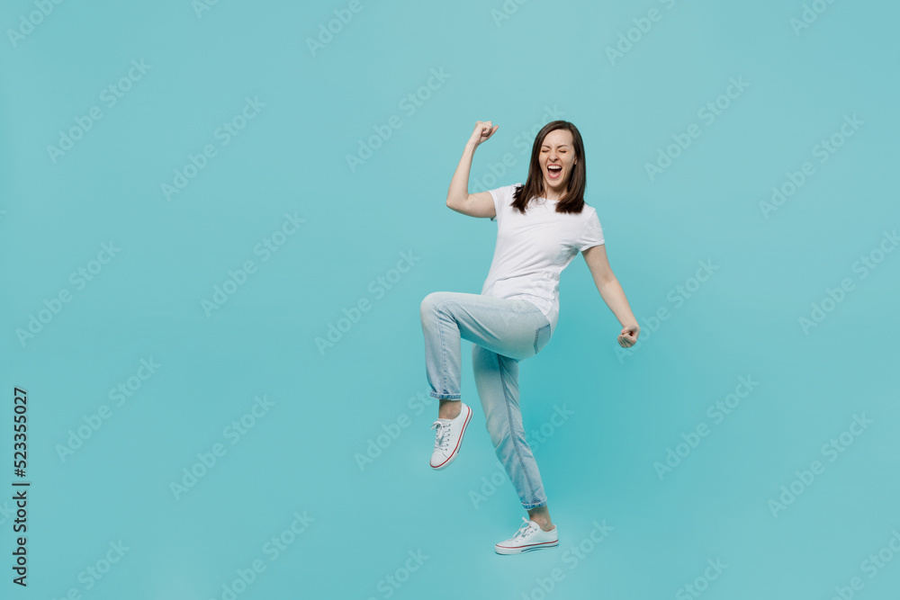 Full body side view young woman 20s she wear white t-shirt doing winner gesture celebrate clenching fists say yes isolated on plain pastel light blue cyan background studio. People lifestyle concept. Full body side view young woman 20s she wear white t-shirt doing winner gesture celebrate clenching fists say yes isolated on plain pastel light blue cyan background studio. People lifestyle concept.