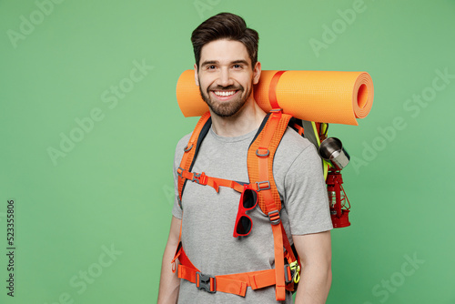 Young smiling mountaineer traveler white man carry backpack stuff mat isolated on plain green background Tourist leads active healthy lifestyle walk on spare time Hiking trek rest travel trip concept