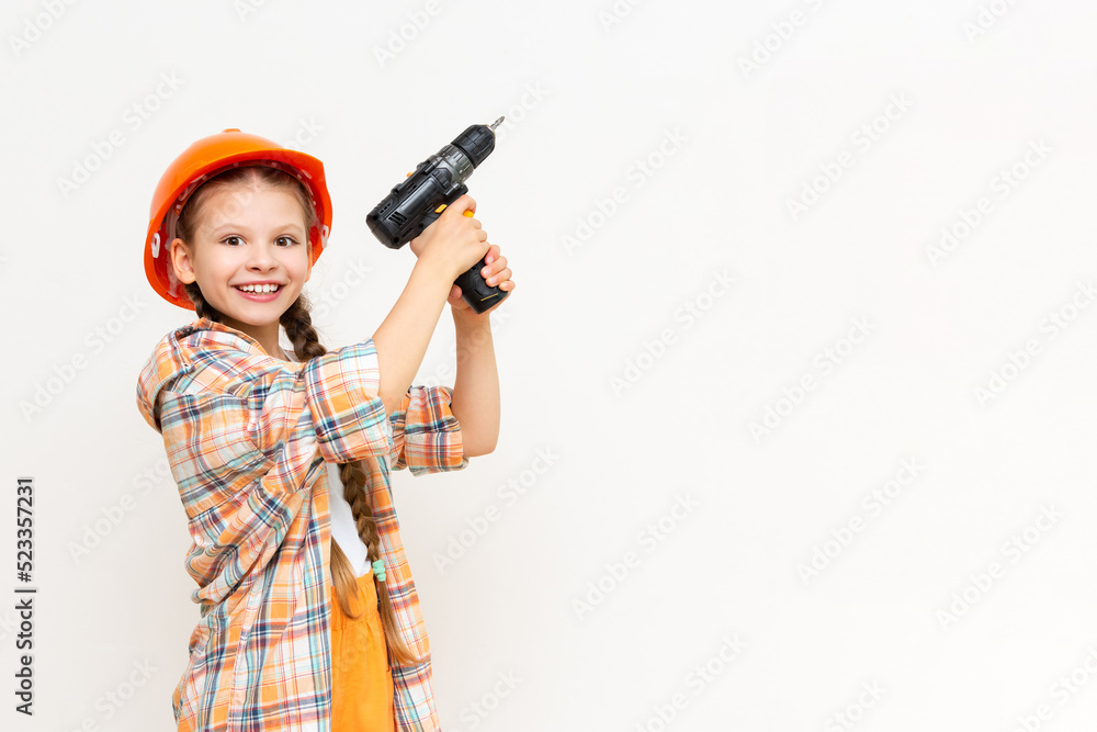 A little girl with a drill in her hands to show your advertisement on a white isolated background. The concept of renovation in the children's room. Copy space. A little girl with a drill in her hands to show your advertisement on a white isolated background. The concept of renovation in the children's room. Copy space.