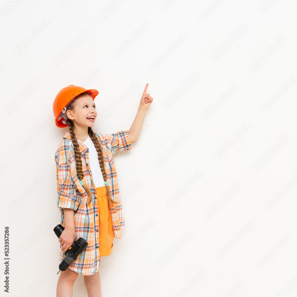 A little girl with a drill in her hands to show your advertisement on a white isolated background. The concept of renovation in the children's room. Copy space. A little girl with a drill in her hands to show your advertisement on a white isolated background. The concept of renovation in the children's room. Copy space.