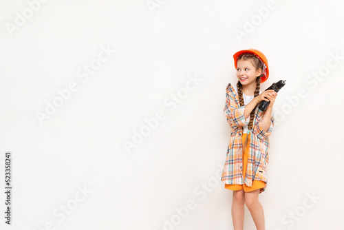 A little girl with a drill in her hands to show your advertisement on a white isolated background. The concept of renovation in the children's room. Copy space. © Юлия Дьякова